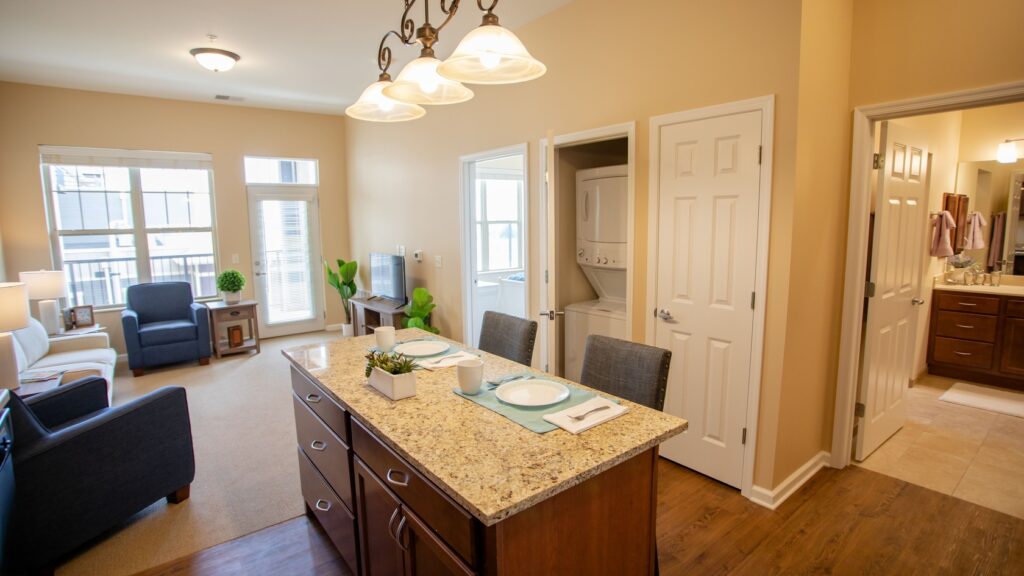 Apartment with granite countertops, place settings, a living room, and a washer/dryer.