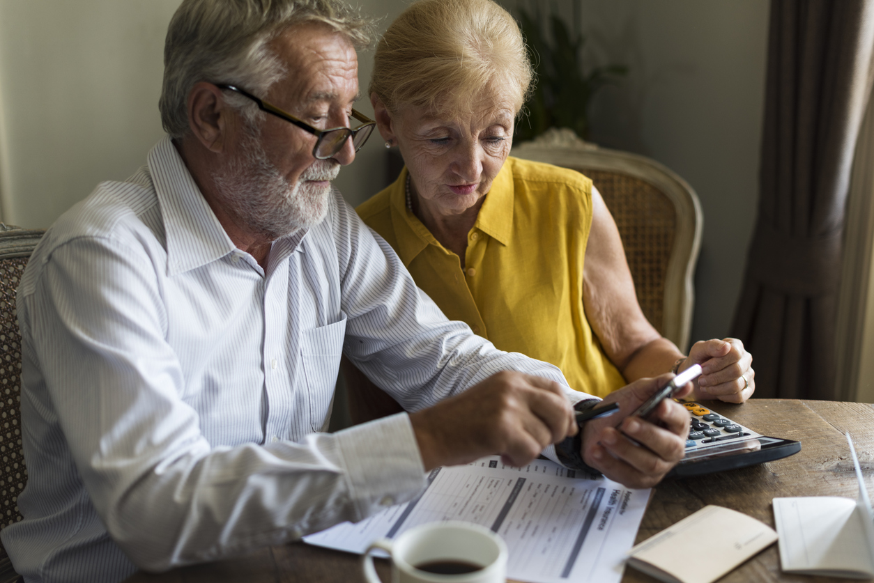 Older adult couple using a calculator and filing papers